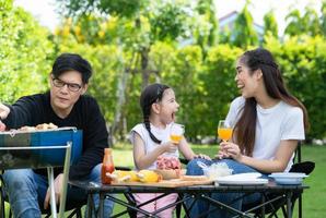 Family holiday activities include father, mother and children with camping barbecue and play in the yard together happily on vacation. photo