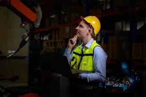 A male engineer checking the operation of a welding robot. used for precision welding control Fast and highly secure photo