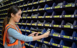 Female warehouse worker Counting small parts stored in the blue storage compartment. to check the remaining amount in order to prepare for the next order photo