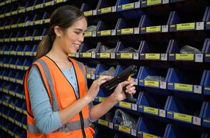 Female warehouse worker Counting small parts stored in the blue storage compartment. to check the remaining amount in order to prepare for the next order photo