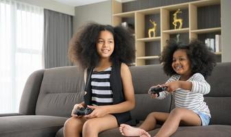dos hermanos de una familia asiático-afroamericana. relajarse y jugar juegos en línea en la sala de estar de la casa. foto