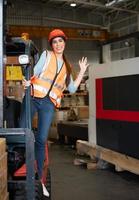 retrato de una mujer asiática con un montacargas usado para levantar objetos pesados en un almacén. foto