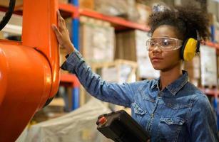 A young female worker is controlling a mechanical robot. to sort out the items that come into the warehouse to wait for the next shipment. photo