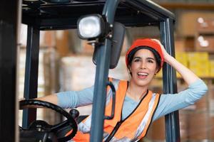 retrato de una mujer asiática con un montacargas usado para levantar objetos pesados en un almacén. foto