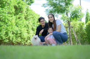 familia asiática con padre, madre e hija divirtiéndose alegremente en el jardín de la casa foto