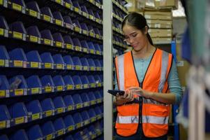 Female warehouse worker Counting small parts stored in the blue storage compartment. to check the remaining amount in order to prepare for the next order photo