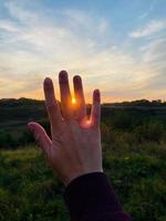 mano sobre el fondo de la puesta de sol foto