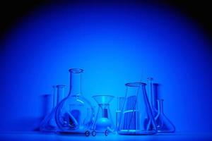 equipo de vidrio de laboratorio de ilustración 3d, tubos de ensayo y matraces sobre fondo azul. cristalería de laboratorio para investigación médica o científica. frascos vacíos, vasos. foto