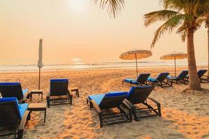 umbrella chair beach with palm tree and sea beach at sunrise times photo