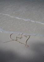 corazones dibujados en la arena de una playa foto