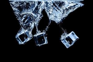 cubos de hielo en agua sobre fondo oscuro de estudio. el concepto de frescura con frialdad de cubitos de hielo. foto