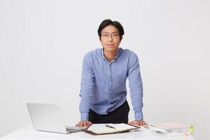 Handsome confident asian young businessman in glasses having video conversation using laptop and earphones looking at camera over white background photo