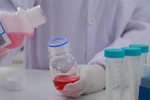 Woman scientist biochemist at the workplace makes the analysis in the modern laboratory. She is holding a dropper and a test tube photo