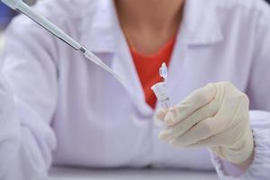 Woman scientist biochemist at the workplace makes the analysis in the modern laboratory. She is holding a dropper and a test tube photo