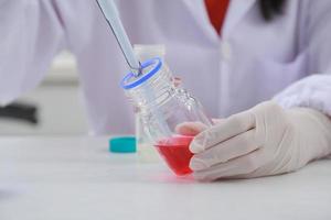 Woman scientist biochemist at the workplace makes the analysis in the modern laboratory. She is holding a dropper and a test tube photo