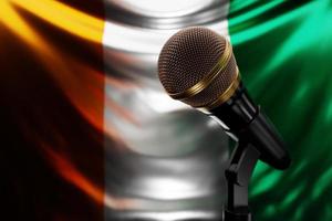 Microphone on the background of the National Flag of Cote d'ivoire, realistic 3d illustration. music award, karaoke, radio and recording studio sound equipment photo