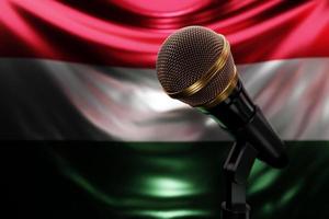 Microphone on the background of the National Flag of Hungary, realistic 3d illustration. music award, karaoke, radio and recording studio sound equipment photo