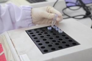 Woman scientist biochemist at the workplace makes the analysis in the modern laboratory. She is holding a dropper and a test tube photo