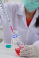 Woman scientist biochemist at the workplace makes the analysis in the modern laboratory. She is holding a dropper and a test tube photo