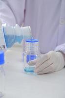 Woman scientist biochemist at the workplace makes the analysis in the modern laboratory. She is holding a dropper and a test tube photo