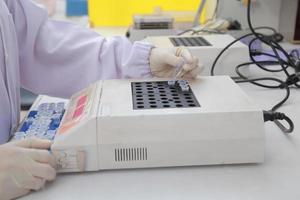 Woman scientist biochemist at the workplace makes the analysis in the modern laboratory. She is holding a dropper and a test tube photo