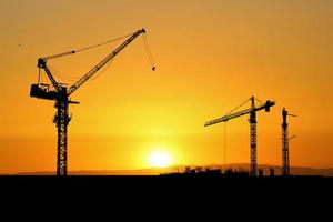 Silhouette of a crane in a construction site. Crane concept for the construction industry photo