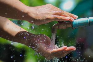 Water concept in everyday life. Hands supporting the water flowing from the faucet. water splashing from the tap photo