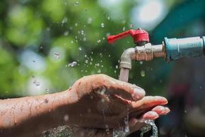 Water concept in everyday life. Hands supporting the water flowing from the faucet. water splashing from the tap photo