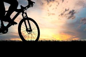 siluetas de bicicletas de montaña y ciclistas por la noche felizmente. concepto de viaje y fitness. silueta de ciclistas recorriendo el concepto de cicloturismo vespertino foto