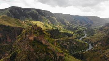 inzoomen dramatisch landschap met historische tmogvi-fortruïnes met oude muur op heuveltop omgeven schilderachtige mtkvari-rivier en canyon-panorama video