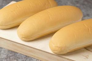 Close up long bread for hot dogs on a wood plate. photo