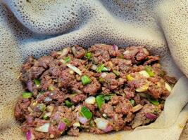 raw beef Ethiopian delicacy named kitfo with bread and peppers photo