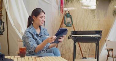 una hermosa mujer asiática está feliz de pintar en una tableta. 4k dci el metraje enviado es un arreglo de filmación grupal video