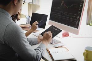 An investment expert points a pen at a computer monitor to analyze the stock market to teach you how to make a profit. photo