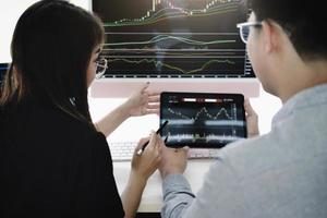 An investment expert points a pen at a tablet monitor to analyze the stock market to teach you how to make a profit. photo