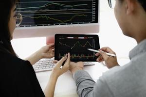 An investment expert points a pen at a tablet monitor to analyze the stock market to teach you how to make a profit. photo