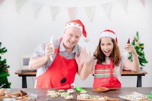 A European girl and her father are wearing gingerbread paint makeup that she finishes for Christmas and New Year photo