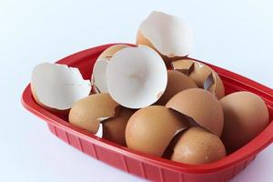 Broken eegshells in red container on white background photo