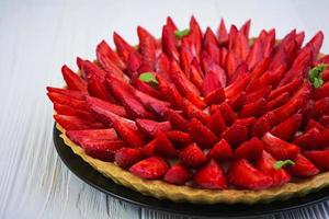 Delicious tart with strawberry on wooden background photo