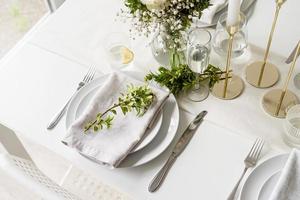 The wedding table setting, high angle view . Wedding teble decoration with white roses and boxwood photo