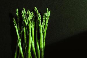 Green fresh asparagus isolated on black background. photo