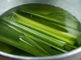 hojas de pandan y pandan en una taza de madera preparada para hervir o secar jugo de pandan o pastel de pandan antes de ir a cocinar. filmado en el estudio foto