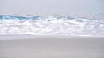 Wellen des blauen Meeres, türkisfarbene Meereswellen, die sich an der sandigen Küste brechen. Goldener Strand trifft auf tiefblaues Ozeanwasser und schäumende Wellen. video