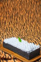 Chocolate Sponge Cake filled with whipped cream on white plate with fork photo