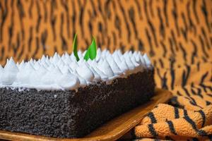 Chocolate Sponge Cake filled with whipped cream on white plate with fork photo