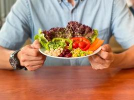 Man hands holding a green salad. Healthy lifestyle and vegetarian vegan, Intermittent Fasting concept. photo