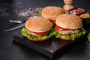 Three hamburger with beef meat burger and fresh vegetables on dark background photo