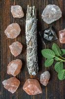 group of healing objects of smudge sage stick, pink salt crystals, and fresh sage with copy space flat lay photo