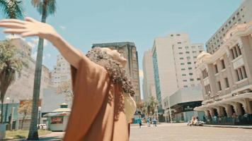 jeune femme latine tournant à bras ouverts au centre d'une ville. Cinématique 4k. video