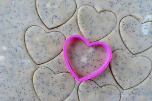 galletas de mantequilla en forma de corazón feliz con cortador de galletas rosa foto
